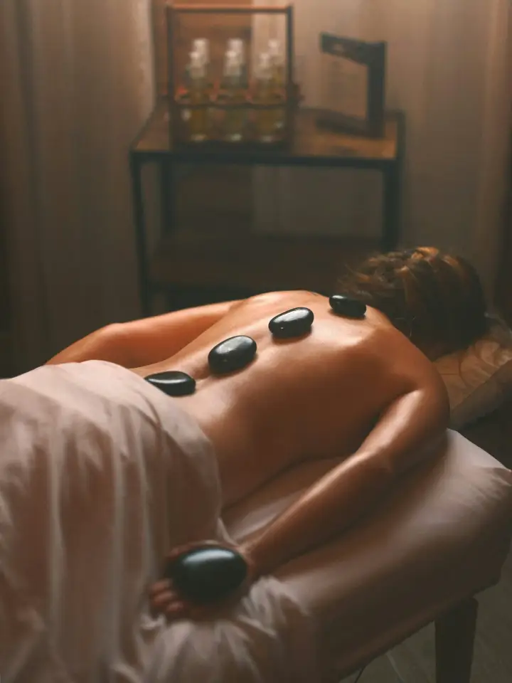 Sıcak taşların bulunduğu sakin bir spa ortamında masaj deneyimi